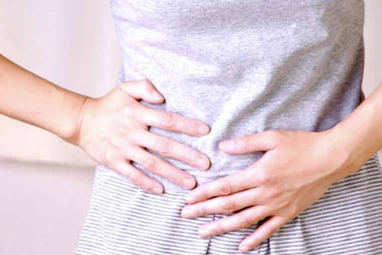 personne qui se tient le ventre à deux mains