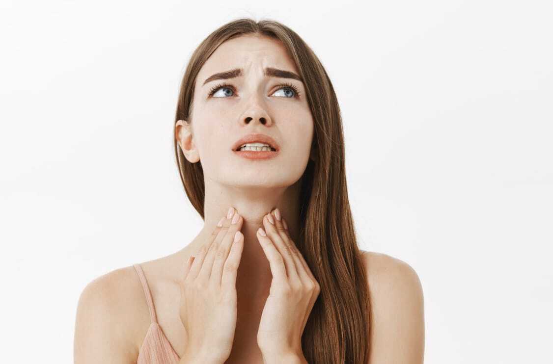 femme brune qui se tient la gorge à 2 mains
