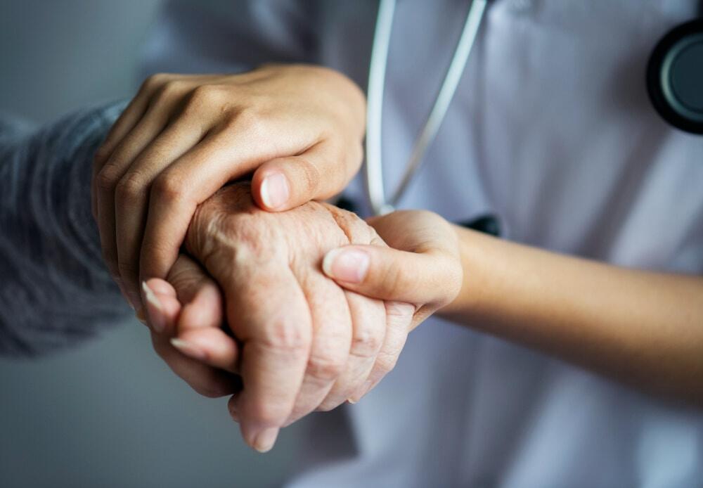 Mains de jeune femme qui tient la main d'une personne âgée